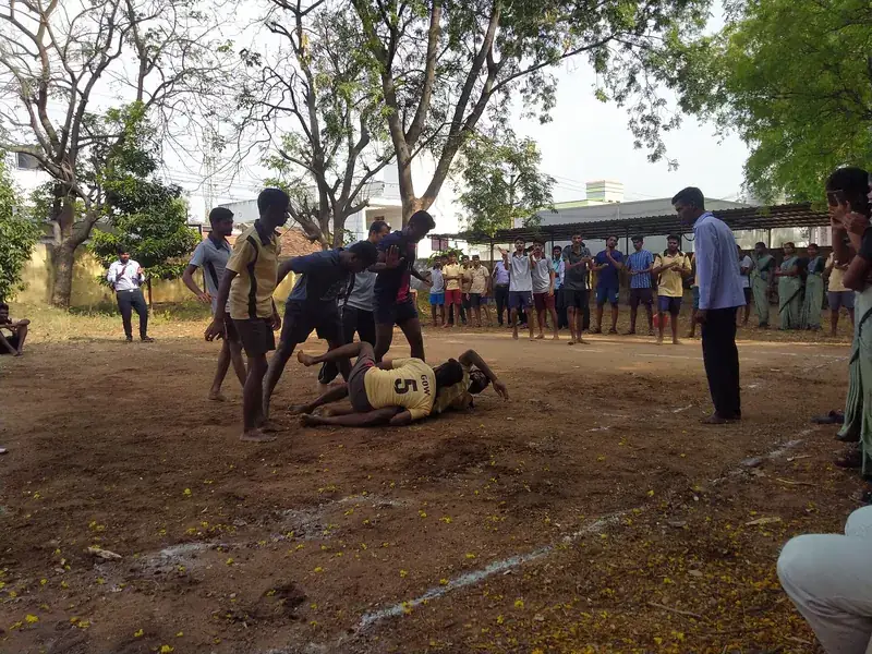 A kabaddi match on a dirt ground with spectators.